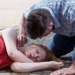 A man checks the pulse of a fainting girl